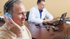 Man wearing headphones with clinician monitoring him