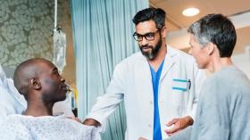 male healthcare worker speaking with male patient on hospital bed 