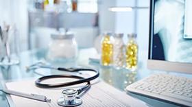 stethoscope, pen, medication bottles, on top of paperwork  