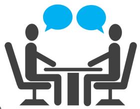 2 stick figures sitting at a table facing each other 